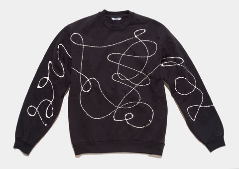 100% cotton black sweatshirt, perfectly cut, has scrawled, drippy white hand-painted line that runs across body and sleeves