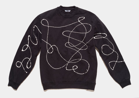 100% cotton black sweatshirt, perfectly cut, has scrawled, drippy white hand-painted line that runs across body and sleeves 
