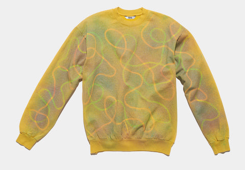 100% cotton gold sweatshirt, perfectly cut, has a neon green and orange meandering line across the body and down the sleeves. A colorful ombre spray serves as a backround. The composition continues on the other side of the shirt.