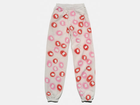 100% cotton light grey/cement sweatpants, perfectly cut, with hand-painted, pink and red, negative cut-out squares extending across body and down legs. The pattern continues on the other side of the pants. 